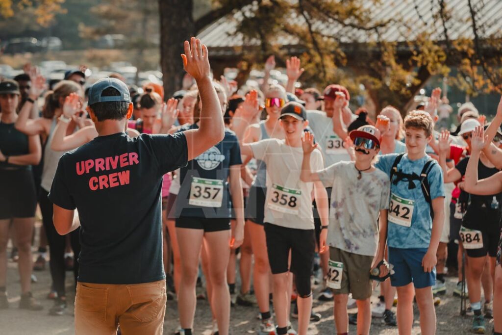 Upriver Running race official raising a hand to a crowd of runners at a race start line in Thunder Bay, sports event photography